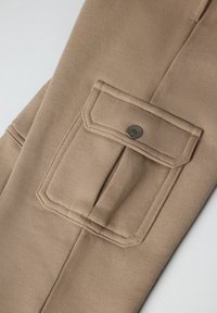 Beige bomuldsbukser med en rektangulær lomme med metaltrykknap, struktureret stof og lige ben-design.