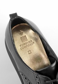 Černá kožená bota s kulatou špičkou, hladkým povrchem a zlatou stélkou s embosovaným nápisem "Forever Comfort".