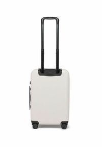 Valise rigide blanche avec poignée et roues noires, présentant un extérieur lisse et une poignée rétractable, conçue pour le voyage.