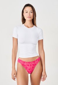 White short-sleeve shirt paired with pink sheer ruffled underwear. The shirt has a simple round neckline, and the underwear features a floral pattern.