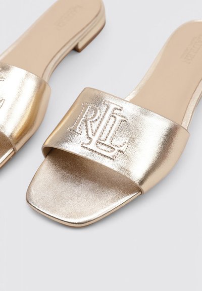Sandalias deslizantes metálicas doradas con una tira ancha que presenta el logo "RL" en relieve, suela plana y textura suave.