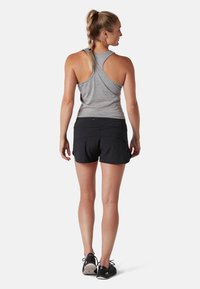 Harmaa hihaton urheilu toppi ja mustat shortsit, joissa on istuva muotoilu ja pehmeä rakenne. Näkyvää verkko-osiota takana.