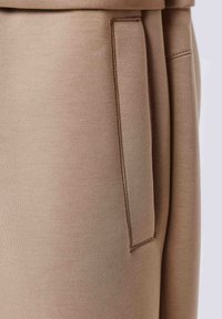 Beige broek van zachte stof met een zijzak, een strak gestroomlijnd ontwerp en zichtbare stiksels.