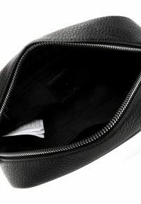 Pochette nera in pelle con superficie testurizzata, dotata di chiusura con zip e fodera interna liscia. Include un piccolo cartellino informativo all'interno.
