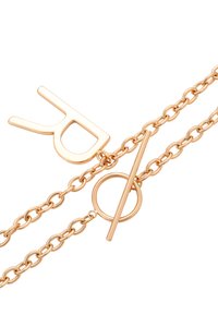 Guldtonet metalarmbånd med kædedesign og toggle-lukning. Bemærkelsesværdige detaljer inkluderer en fredstegnscharme og cirkulære accenter.