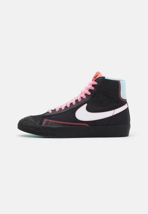 Sort høj-top sneaker med lyserøde snørebånd, hvid Nike swoosh, rød syning og en lyseblå polstret krave på en hvid baggrund.