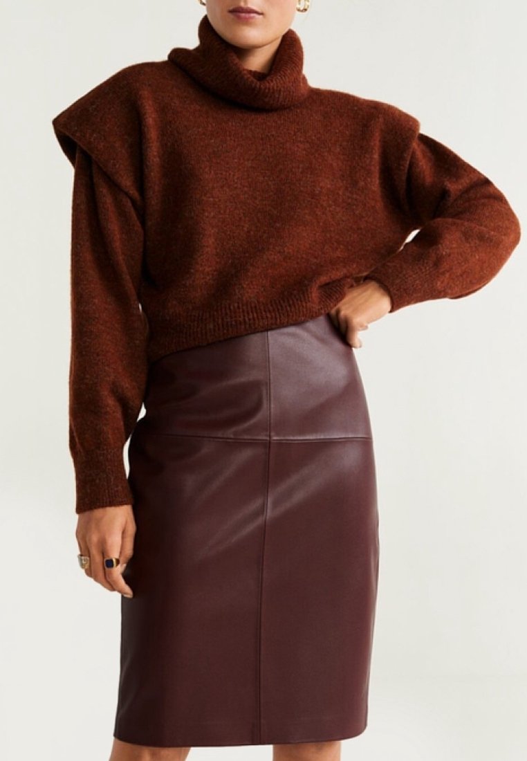 Ruskea pooloneule yläosa, jossa löysä istuvuus ja olkapääkoristeet, yhdistetty tiukasti istuvaan viininpunaiseen nahkaiseen lyijykynähameeseen. Pehmeä tekstuuri, virtaviivainen muotoilu.