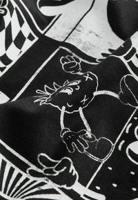 Tissu noir et blanc avec un personnage de dessin animé présentant un visage cousu, un poing levé et des mains gantées dans un design graphique patchwork.