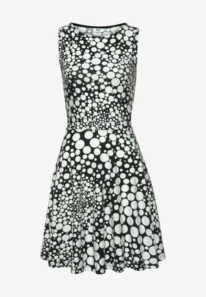 Schwarz-weiße Kleid mit ärmellosem Design, das ein Muster aus unterschiedlich großen Kreisen aufweist. Der Stoff wirkt glatt und leicht.