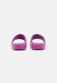 Lila slip-on skor med en slät yta och rund häl. Har sidoventilationshål för andningsförmåga. Lättviktsdesign.