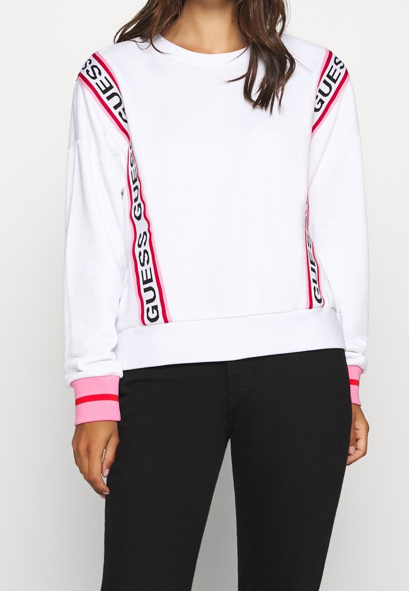 Sudadera blanca con franjas laterales estampadas en rosa y negro, puños de canalé rosa, cuello redondo y ajuste relajado.