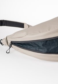 Beige Stoff Bauchtasche mit einem schwarzen Reißverschluss und Netzfutter; geschwungene Form; verstellbarer schwarzer Riemen; mit einem Zugband für eine einfache Handhabung.