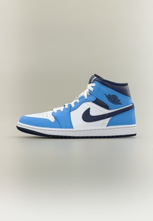 Pantof sport Nike Air Jordan cu gleznă înaltă, alb, albastru deschis și bleumarin, cu sigla neagră și șireturi negre, afișat pe fundal neutru.