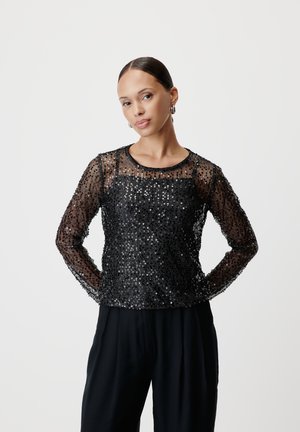 Black sequined top with long sheer sleeves, round neckline, textured surface, and a fitted silhouette. Paired with black trousers.