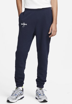 Pantalones deportivos azul marino con cintura ajustable, bolsillos laterales y puños en los tobillos; cuentan con un logotipo blanco en la pierna izquierda; fabricados con una mezcla suave de algodón.