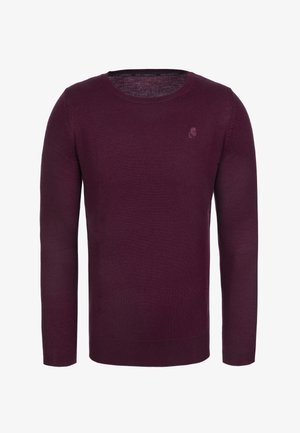 Burgundský pletený svetr s dlouhými rukávy a kulatým výstřihem. Na hrudi je jemné logo. Hladká textura a přiléhavý střih.