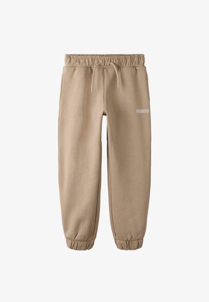 Pantalon de jogging beige en tissu doux, doté d'une taille et de poignets élastiques, avec un petit logo réfléchissant sur le côté.