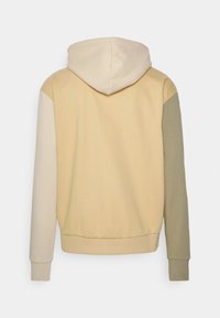 Hooded sweatshirt med en färgblockerad design som har ljusbeige, krämfärgade och olivgröna paneler. Tillverkad av mjukt material med ribbade mudd. 