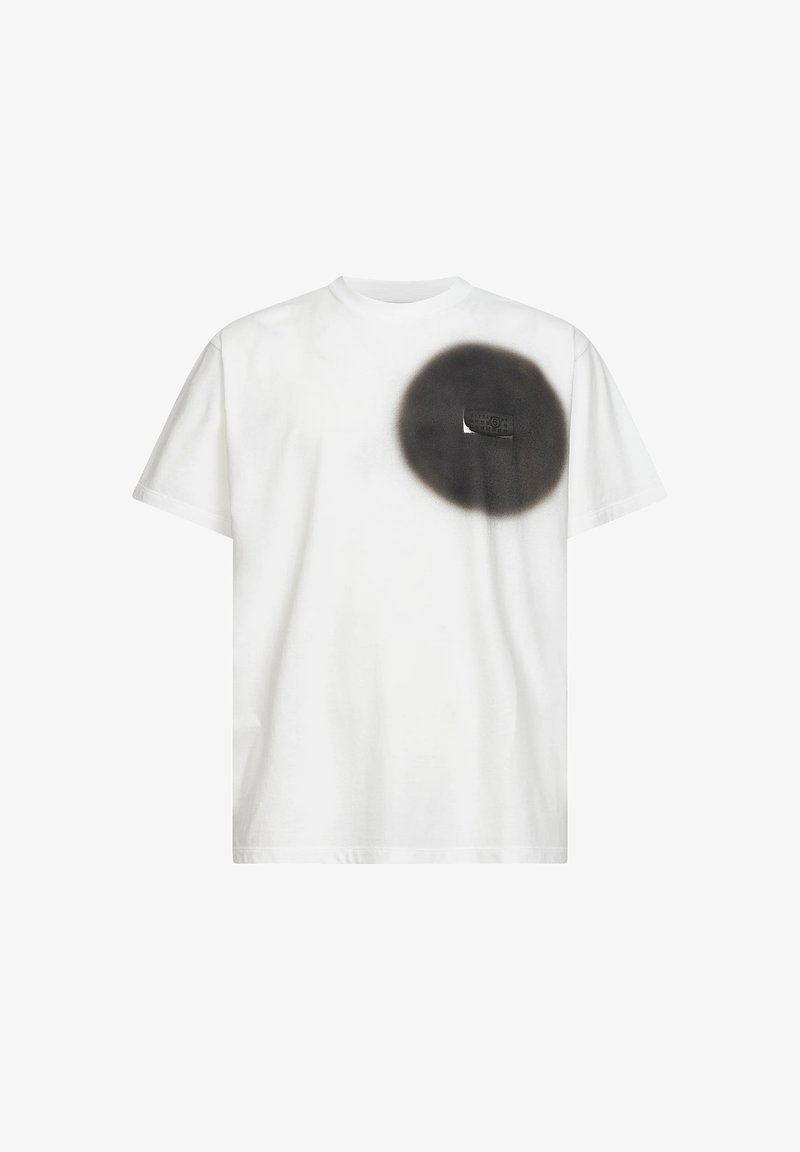 Camiseta blanca de manga corta con un círculo negro pintado con spray en el lado izquierdo del pecho y un pequeño bolsillo parcialmente visible dentro del círculo.