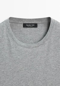 Lichtgrijs T-shirt met ronde hals, zichtbare naadstiksels en een zwart label met de tekst "Massimo Dutti Made in Portugal" aan de binnenkant van de kraag.