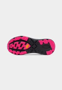 Talpa încălțămintei pentru alergare pe trasee, cu cauciuc negru și roz aprins, și crampoane adânci, având un logo galben Vibram aproape de zona arcadelor.