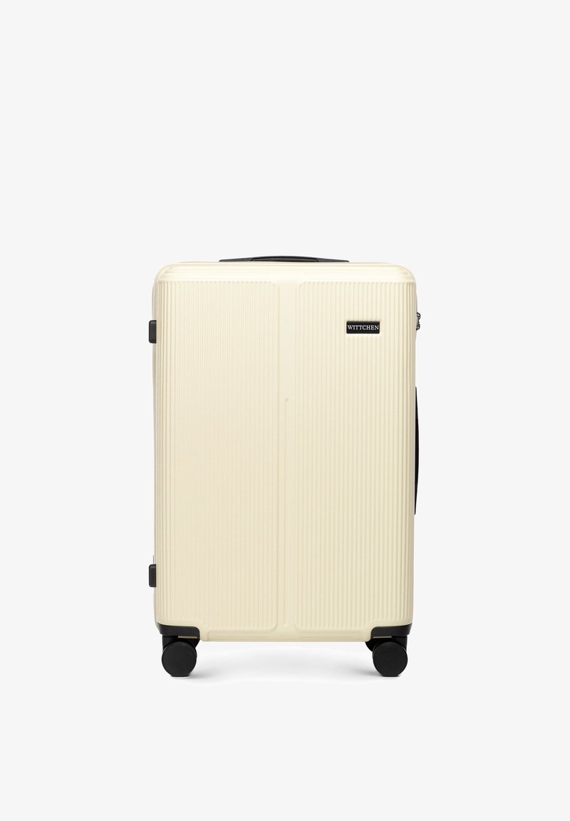 Hard-shell koffer in crème met verticale ribbels, zwarte accenten en vier zwarte wielen voor gemakkelijke mobiliteit. Voorzien van een handvat bovenop.