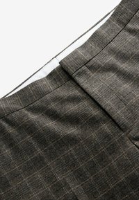 Grau kariierte Hosen aus strukturiertem Stoff mit einer glatten, weißen Bundinnenseite und flachem Vorderdesign.