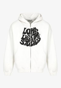 Felpa bianca con zip e cappuccio, caratterizzata da un grande design grafico in nero con la scritta "LOW LIGHT STUDIOS". Include un cappuccio e tasche frontali.
