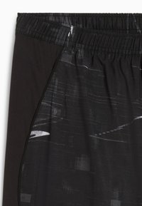 Schwarze Sportshorts mit einem strukturierten Bund, einem abstrakten grauen Muster und einem kontrastierenden einfarbigen schwarzen Seitenpanel.