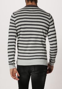 Grå och svart randig tröja; ribbad krage och ärmslut, figursydd design, mjukt material, enfärgade detaljer vid halsringningen och i nederkant.