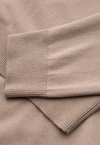 Maglione a maglia di un colore beige chiaro con polsini e orlo a coste. Tessuto morbido, con una finitura liscia e dettagli di cucitura puliti.