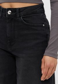 Svarta denimjeans med hög midja, framfickor och silverknapp. Slät textur och rak bendesign.