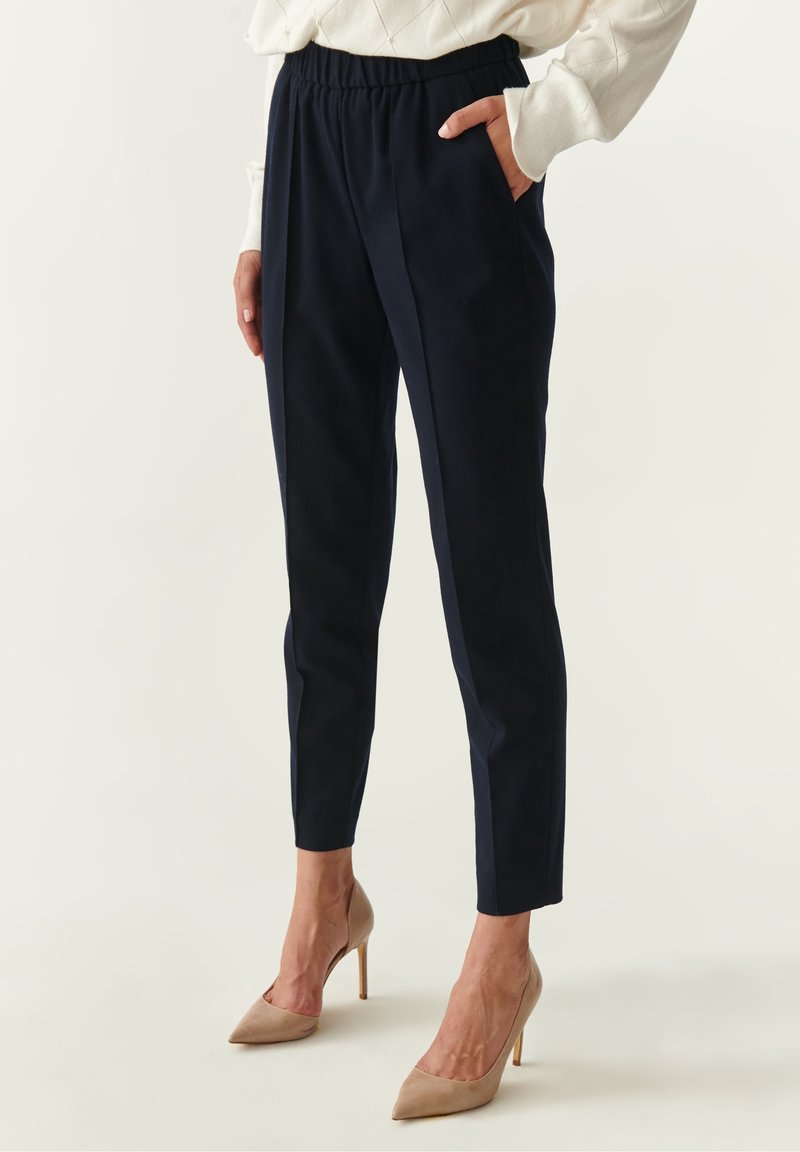 Tmavě modré, elastické kalhoty s elastickým pasem a bočními kapsami; slim fit design v kombinaci s tělovými lodičkami.