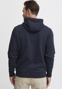 Söt�étkék kapucnis pulóver pamut keverékből, állítható kapucnival, bordás mandzsettával és fitted derékkal. Simább tapintás, minimális részletezéssel.