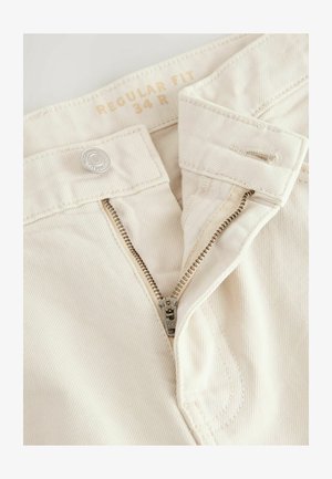 Pantaloni beige dalla vestibilità normale con chiusura a zip metallica e bottone, caratterizzati da un tessuto leggermente testurizzato e dettagli di cucitura. Etichetta di taglia visibile.