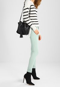 Svartvit randig tröja, mintgrön smal byxor, svarta ankelstövlar och en svart bucketbag med en tofs.