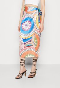 Jupe portefeuille colorée ornée de divers motifs circulaires en bleu, orange, rose et vert. Elle dispose d'un lien à la taille et atteint une longueur mi-mollet.