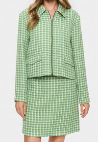 Zelená a bílá károvaná bunda s límečkem, předním zipem a dvěma bočními kapsami, doplněná odpovídající sukní do kolen.