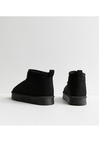 Czarne zamszowe botki za kostkę o chropowatej powierzchni, z zaokrąglonymi noskami i gumową podeszwą. Posiadają pętelkę z tyłu ułatwiającą zakładanie.