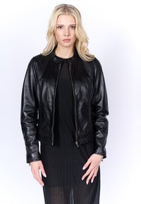 Zwarte leren jas met een ronde halslijn, ritssluiting en lange mouwen. Soepele textuur en aansluitend ontwerp met een cropped snit.