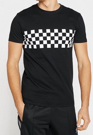 Camiseta de algodón negra con un patrón de cuadros blancos horizontales en el pecho. Diseño clásico de cuello redondo y manga corta.