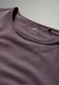 Fialové bavlněné tričko s kulatým výstřihem. Obsahuje štítek s nápisem "THE SET", velikost "M" a "VYROBENÉ V BANGLADÉŠI." Hladká textura.