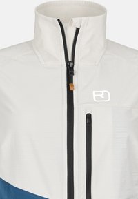 Lightweight, cream-colored jacket with a high collar, black zipper, and blue accents at the bottom. Features a side pocket for storage.