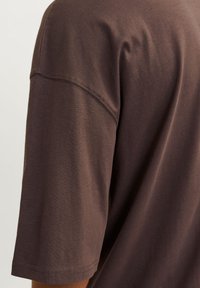 Afslappet brun t-shirt lavet af blødt stof, med rund halsudskæring og korte ærmer med synlig syning.