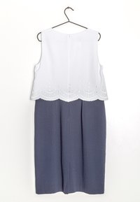 Mouwloze jurk met een witte top met geborduurde accenten en een gegolfde zoom, overgaand naar een donkerblauwe, knielange rok.