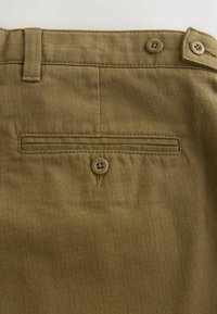 Olive green trousers feature a textured fabric, two front belt loops, and a single back pocket with a button closure.