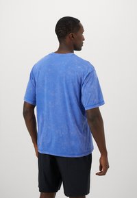 Blue cotton t-shirt with a relaxed fit, short sleeves, and a slightly distressed texture. Back view, plain with no visible logos or patterns.
