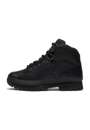 Zwarte leren Timberland enkellaars met gevoerde kraag, metalen veteroogjes en dikke rubberen profielzool, zijaanzicht.