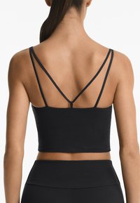 Black cropped top with thin straps, featuring a smooth texture and subtle branding on the back. Designed for athletic wear.