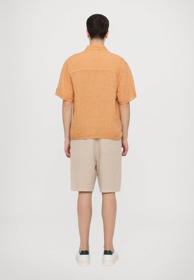 Cămașă din in, cu mânecă scurtă, de culoare portocalie, cu detaliu la spate, asortată cu pantaloni șort din in de culoare bej. Design casual, prezentat din spate.